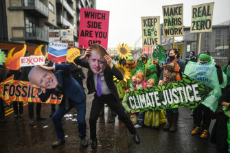 Protesters wearing masks of Boris Johnson and Joe Biden protest outside the entrance to the COP26 site in Glasgow on Friday.