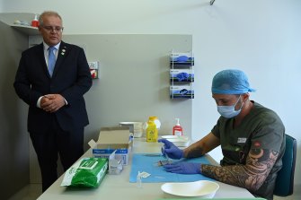 Prime Minister Scott Morrison watches pharmacist Branko Radojkovic prepare a simulated vaccine in Sydney on Friday.