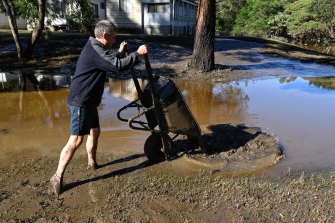 Russell Strickland  clearing mud from his cabin at Leetsvale Caravan Park along the Hawkesbury River.