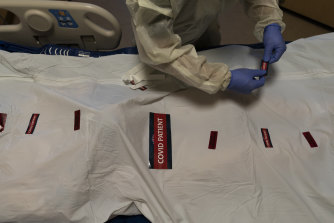 A nurse attaches “COVID Patient” stickers on a body bag of a patient who died of coronavirus in Los Angeles.
