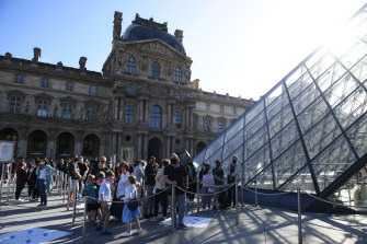 Visitors queue to enter the Louvre in Paris.