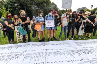 Protesters at the March 4 Justice rally in Melbourne inspecting a list of more than 800 names of women and children killed through domestic violence since 2008.
