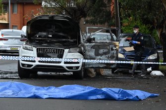 Police examine one of the burnt Audi Q7s in Berala on Wednesday.