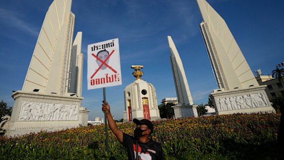 An anti-government protester holds poster which reads “Prayuth get out” in front of Democracy Monument in Bangkok.