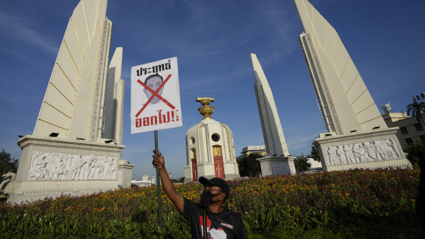 Hükümet karşıtı bir protestocu, Bangkok'taki Demokrasi Anıtı'nın önünde 'Dışarı çık' yazan bir poster tutuyor.