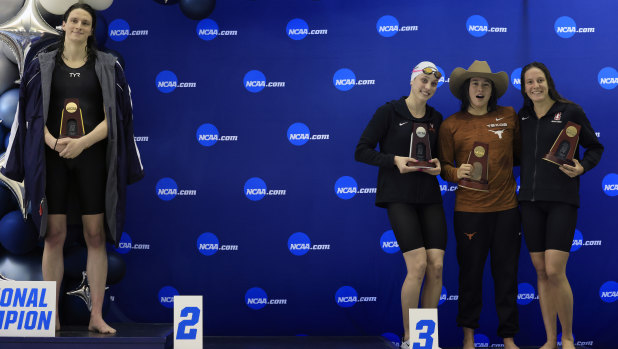 Lia Thomas (left) stands alone on the podium as the other placegetters pose for a group photo.
