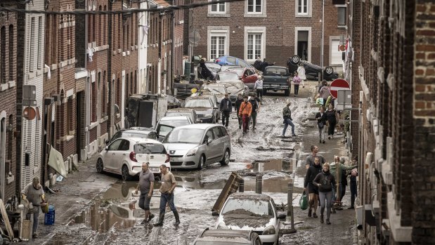 People walk through a damaged street after flooding in Chenee, in Belgium. 