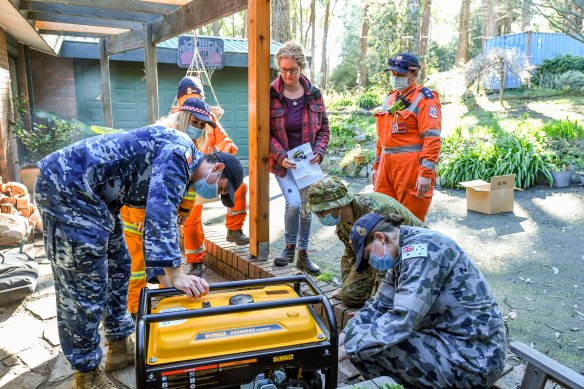 Mount Evelyn resident Therese Harris receives a generator on Monday from an ADF team operating out of Olinda CFA.