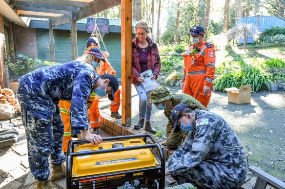 
Mount Evelyn resident Therese Harris receives a generator on Monday from an ADF team operating out of Olinda CFA.