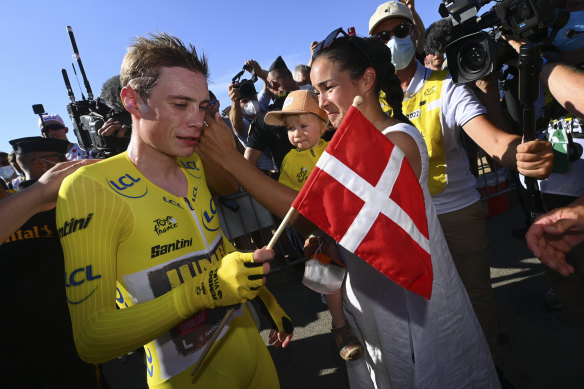 Jonas Vingegaard, wearing the overall leader’s yellow jersey, his wife Trine Hansen, and their child Frida, celebrate after the 20th stage of the race. 