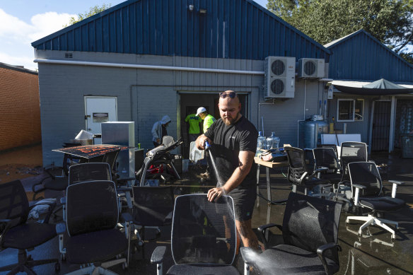 Jack Greene hoses down bins out the back of a business as Picton’s CBD was affected by flash flooding in the early hours of Saturday morning.