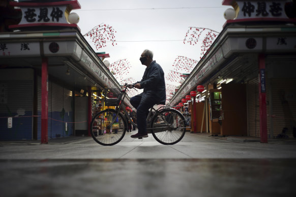 A lone cyclist rides through an empty shopping arcade in Tokyo earlier this year.