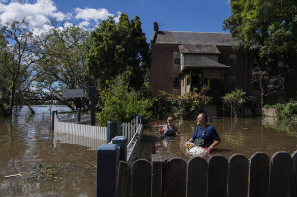 John and Sue Brookes cleaning up floating debris in the backyard of their Thompson Square home in Windsor. 