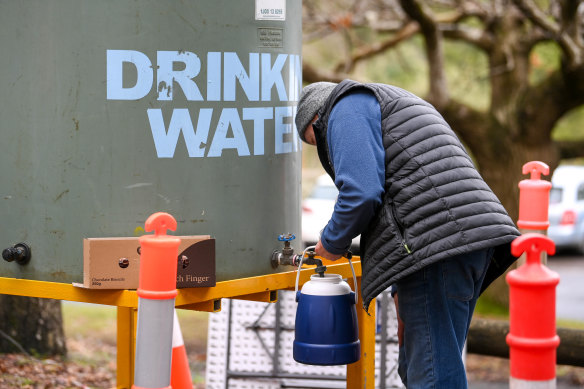A resident of Kallista fills up a container with water brought in by Yarra Valley Water on Wednesday.