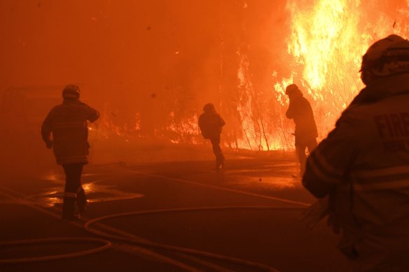 A firefighter stumbles after being hit and is helped back to safety while fighting the Gospers Mountain fire.