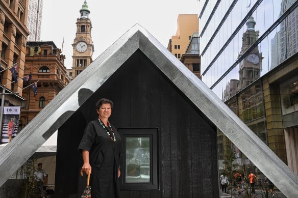 Caroline Pidcock, a cofounder of Architects Declare, looks into a double glazed and insulated room. It is part of the ice block challenge, testing whether ice melts faster in this house compared to another tiny house next to it built to current building standards. 