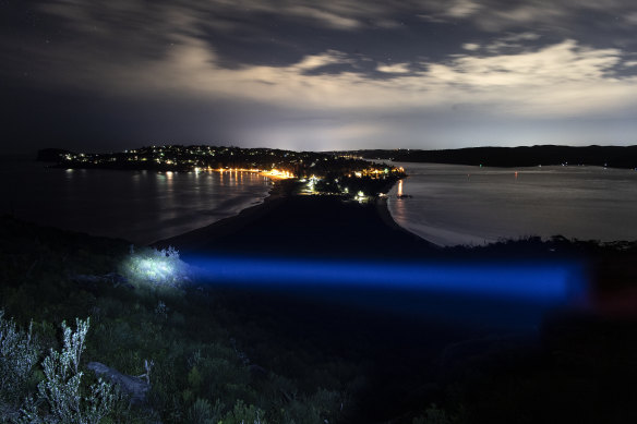 A blue torchlight beam  shines over the view of Palm Beach looking south from the lighthouse.