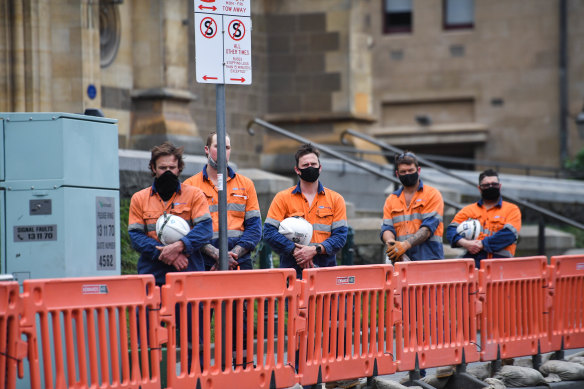 Workers listen to bugler Jason Reeve play the Last Post outside Flinders Street Station on Wednesday.
