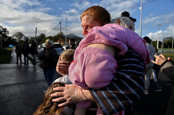Emilee Lamb embraces her children at a vigil for the allegedly murdered boy at Wyong on Monday.
