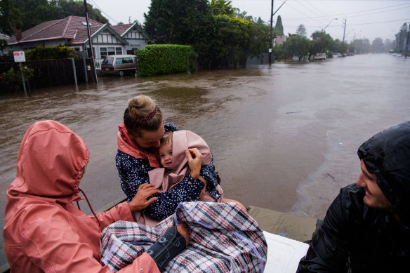 Abbie Bayliss and her daughter Cienna get a lift through flood waters along Pittwater Road, North Manly, in the back of Freshwater man Nick Fraser’s truck.