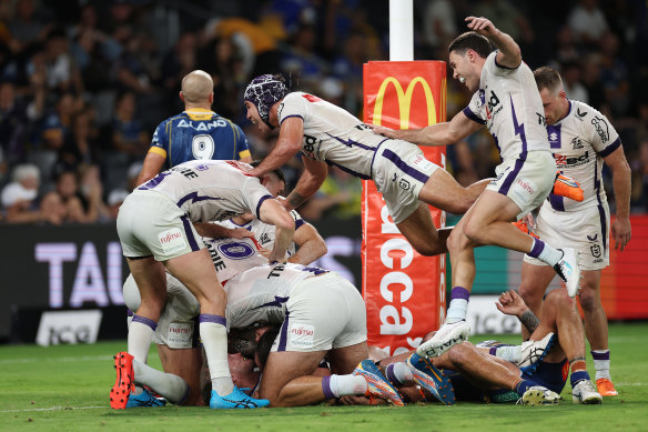 Harry Grant is mobbed by Storm teammates after scoring the winning try.