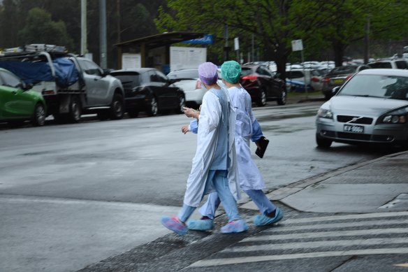 Health workers cross the road near Concord Repatriation General Hospital.