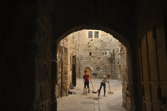 Two boys sweep in the souq, or market, of the old city in Hebron. 