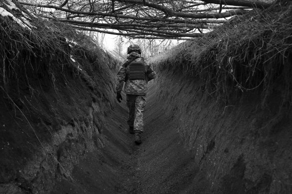 Maksym walks along a trench towards an observation post.