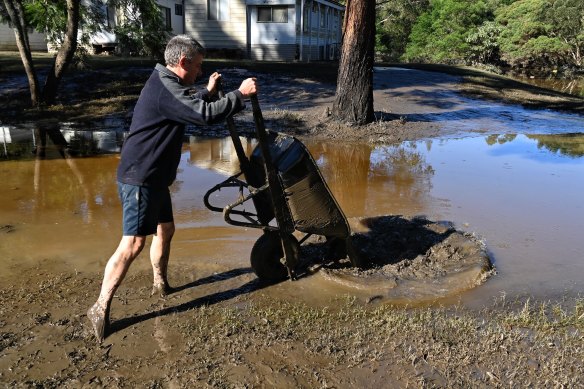 Russell Strickland  clearing mud from his cabin at Leetsvale Caravan Park along the Hawkesbury River.