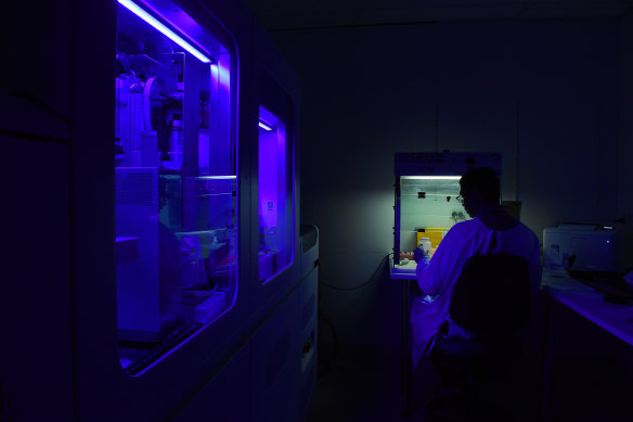 Am instrument, known as COBAS, processing coronavirus samples lights up a virology laboratory as a technical officer carries out general testing. 