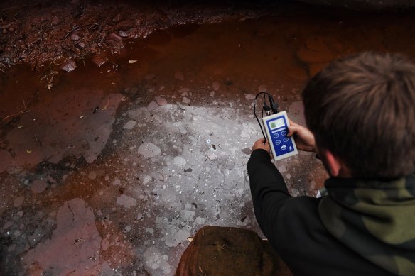 Western Sydney University student Callum Fleming takes samples from a heavily polluted pool on Redbank Creek near the Tahmoor Colliery.

