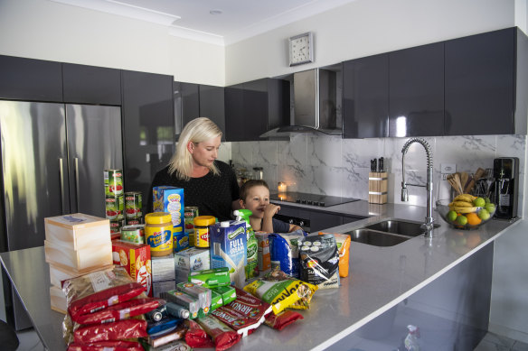 Julie Mason with her son Thomas in her Ermington kitchen with extra groceries.