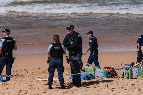 Police at the scene on Saturday, where two pieces of surfboard were taken for further examination.