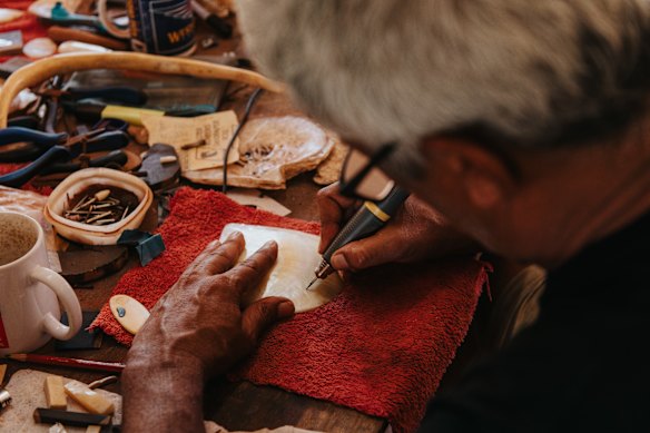 Sibosado in his studio etching into mother-of-pearl shell.
