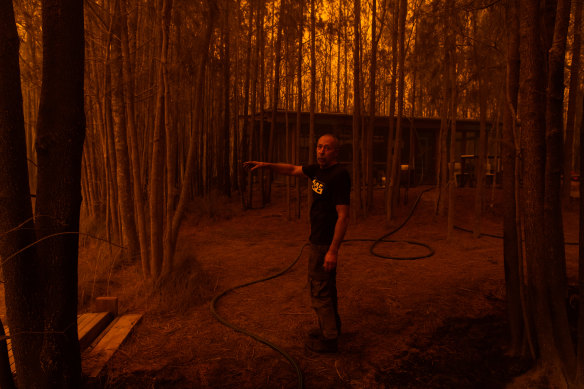 Grant managed to save his property near the Princes Highway. He points towards the dam where he submerged himself for an hour to survive as the fire raged.