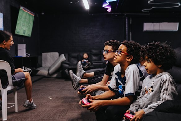 Youth play computer games, handball and futsal in the basement of the centre after prayers.