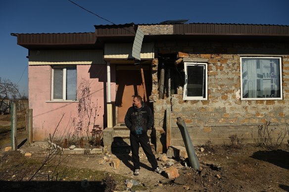 Volodymyr Khala stands next to an unexploded missile that landed in his front yard after hitting his house.