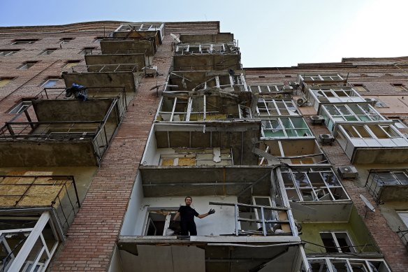 Aleksandr cleans up the debris from his balcony destroyed when the College of Trade building next door was hit by a Russian missile in Bakhmut.