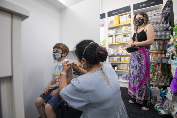 Christine Kelly administers a COVID vaccine to seven-year-old Cohen Doherty, while his mum, Leanne, watches.