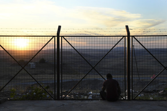 A refugee who has fled Syria into Iraqi Kurdistan looks towards his homeland as the sun sets on the holding centre for undocumented refugees.