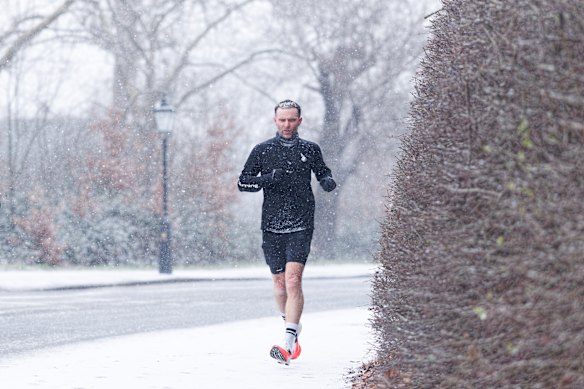 A man jogs through snow in Regent’s Park in London on Tuesday.