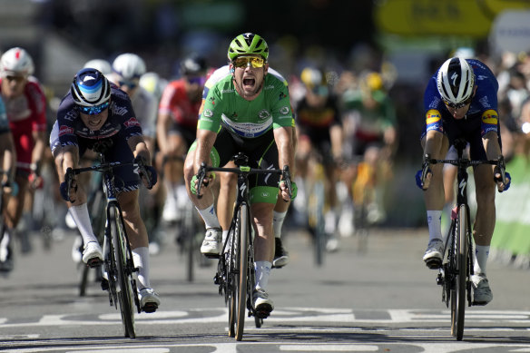 Britain’s Mark Cavendish, wearing the best sprinter’s green jersey, celebrates as he crosses the finish line to win the 13th stage. 