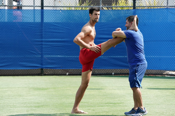 Novak Djokovic stretches following his singles match against Cristian Garin.