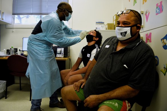 Dr Femi Olutayo (left) gives Ty Boney aged 15yrs (centre) and his father Curtis Boney from Brewarrina COVID-19 tests after they both received their first shot of a vaccination at the Ochre Medical Centre in Brewarrina. 