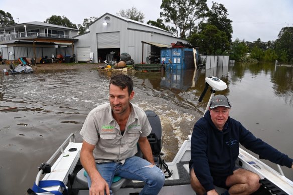 Neighbours Dan Streat and Steve Innes venture out onto floodwaters around Pitt Town.