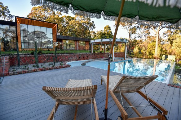 Luke Sheahan’s Eltham home features a tennis court, decking with an infinity pool and an overhanging garden. Adjacent is a sunken lounge, spa, fire pit and a pool house along with a putting green.  