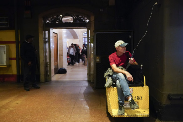 A commuter charges his cell phone while waiting for his train at Grand Central Terminal.