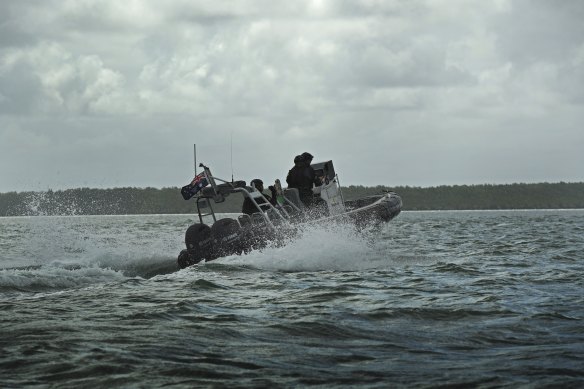 Australian Border Force (ABF) Marine Tactical Officers on a tender boat with the PNG coastline in the background.