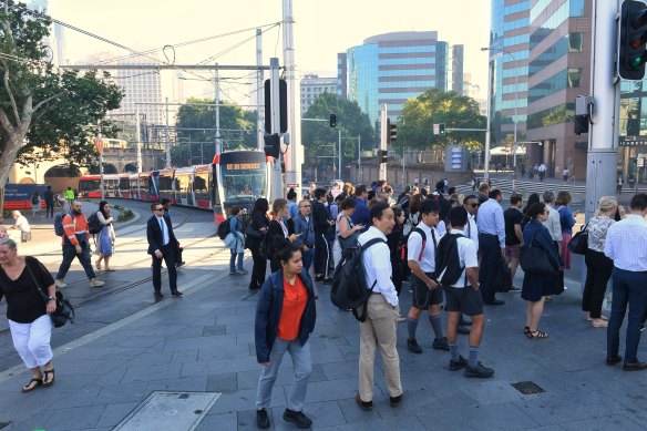 Pedestrians crowd onto a footpath between the light rail line and Elizabeth Street near Central Station.