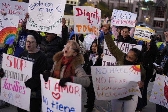 People hold signs during a rally against President Donald Trump’s immigration policies as deportations began.
